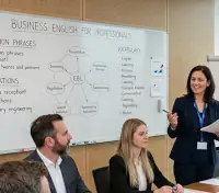 Das Bild zeigt eine betriebliche Schulung, die in einem modernen Büro in Frankfurt am Main stattfindet. Der Raum ist ein zeitgemäßer Konferenzraum mit großen, bodentiefen Fenstern. Durch die Verglasung bietet sich ein freier Blick auf die ikonische Frankfurter Skyline mit ihren charakteristischen Wolkenkratzern.